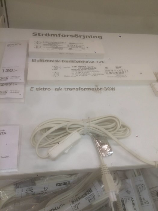 Elektronisk transformator för LED-belysning med sladd och kontakter på hylla, för köksmontering.