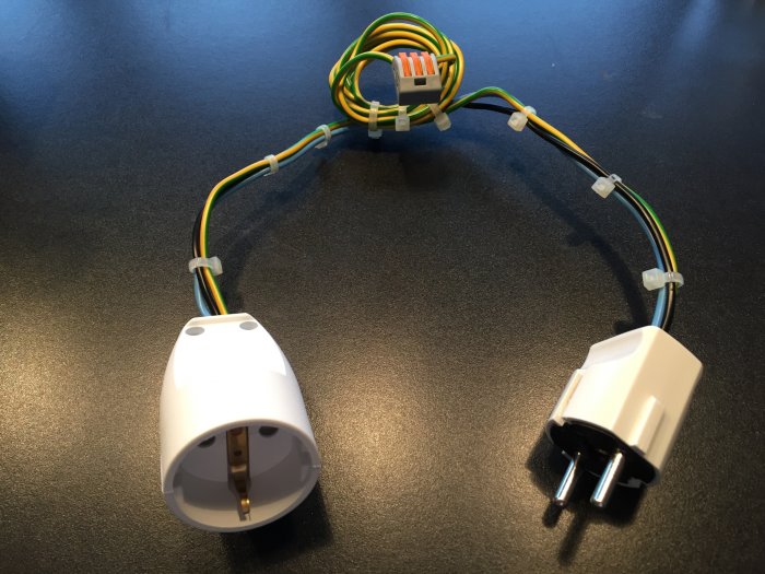 Eladapter med flera varv av slingad kabel ansluten till ett eluttag och en stickkontakt.