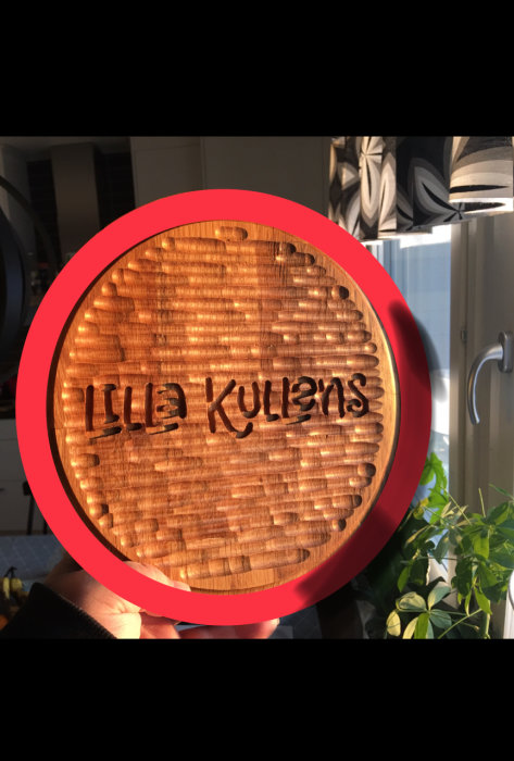 Trästolssits med fräst kant och inbränd text "Lilla Kulens" i heminredningsmiljö.