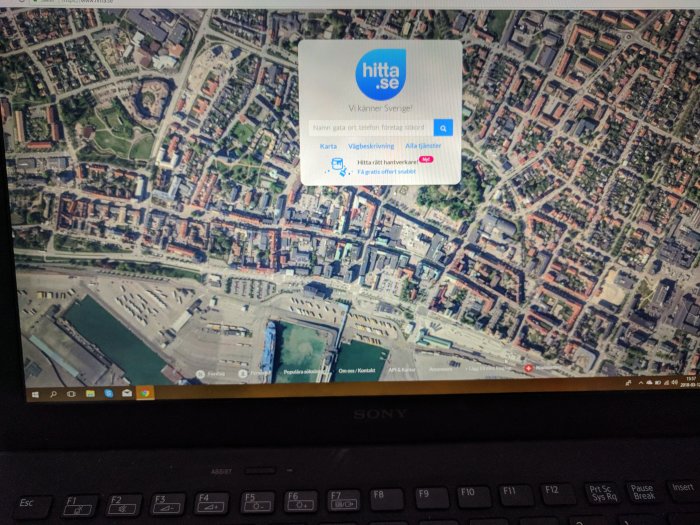 Satellitbild av okänd stad öppnad på Hitta.se på en bärbar dators skärm.