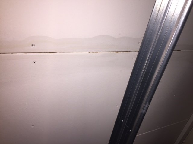 Vattenfläck och plåtspikar på garagets innertak, indikation på läckage.