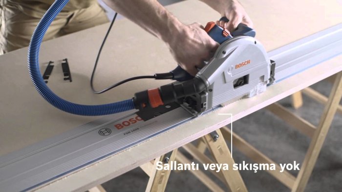 Sänksåg kopplad till ett dammsugaruttag under användning på en träplatta.