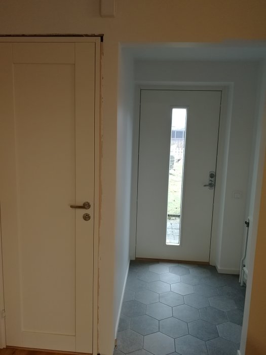 Nymålat rum med slutförda väggar och dörrkarmar, oavslutat tak, synlig ojämn kant vid tak.