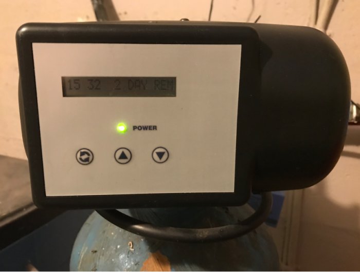 Framsidan av en styrenhet till en vattenfilteranläggning, visar tid och status för tillbakaflöde.