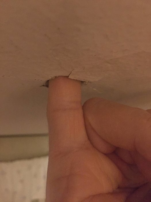 Lillfinger pekar på spänntakets kant nära taklist, visar avståndet mellan tak och vävspänning.