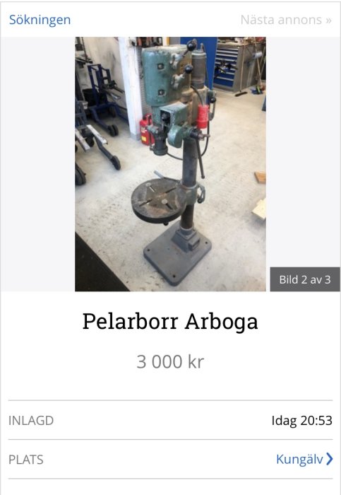 Begagnad pelarborr av märket Arboga står i en verkstadslokal med andra verktyg synliga i bakgrunden.