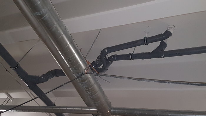 Professionellt installerade rörböjar på tätt förlagda VVS-rör i taket på en byggarbetsplats.