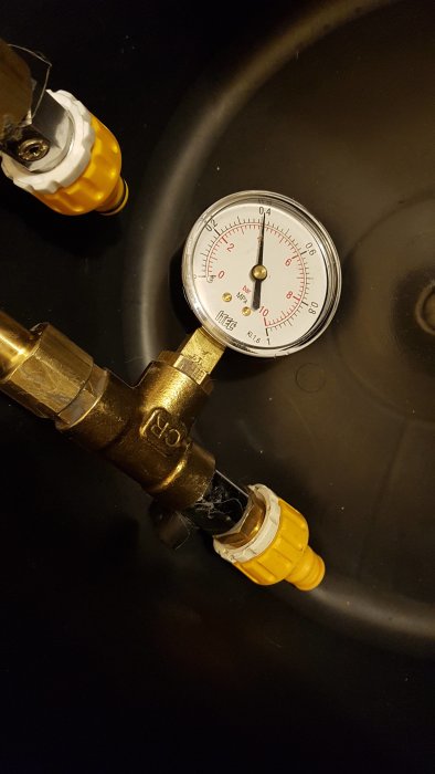 Manometer med mätare kopplad till rörledning som testar vattentrycket.