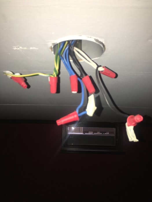 Elektriska kablar sticker ut från taket, redo för installation av taklampa, markerade med tejp.
