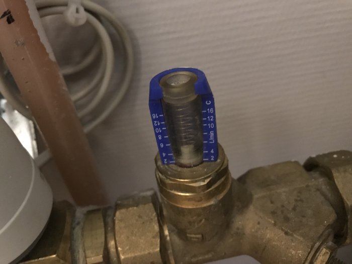 Närbild av en blå mätare på ett ställdon visande 8 liter per minut i en tvättstuga.