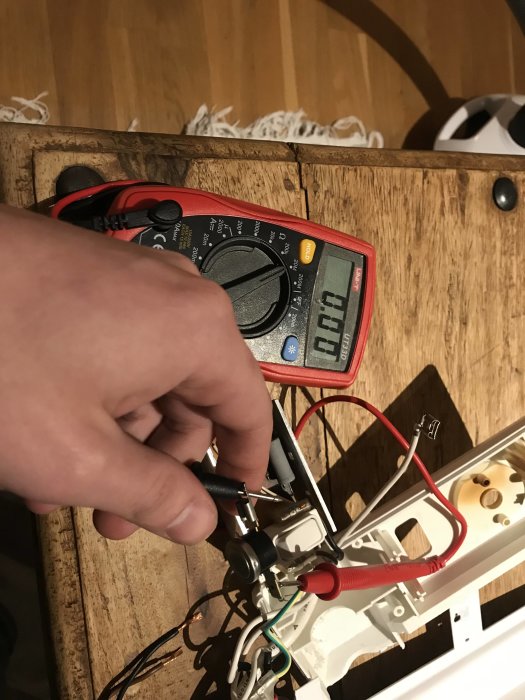 Hand håller en multimeter mot en elektrisk installation med visningen 00.1 på skärmen.