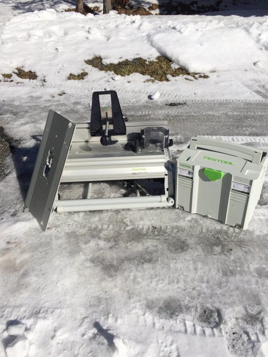 Aluminiumprofiler och en överhandsfräs från Festool på snötäckt mark.