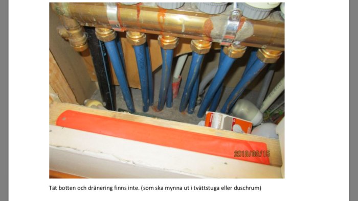 Installationsschakt utan tät botten och dränering visande många rör och kopplingar.