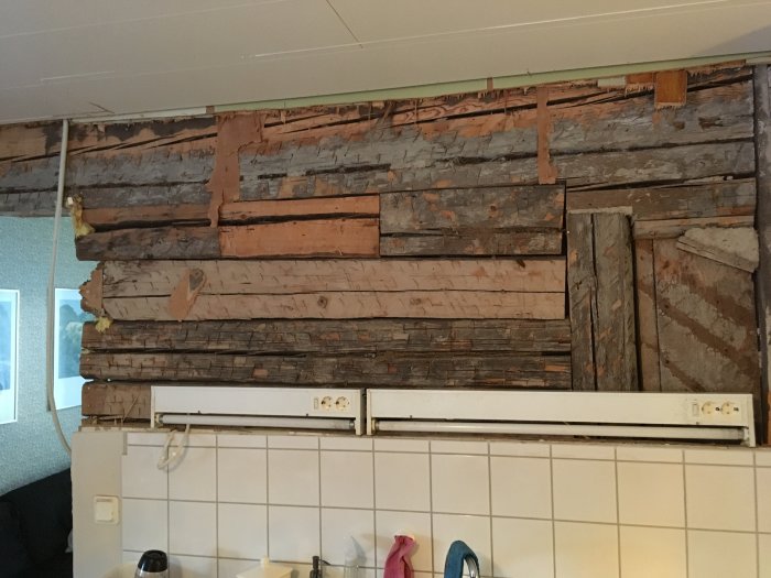 Horisontellt liggande timmer på en vägg med en synlig tidigare dörröppning och stödet mot en murstock.