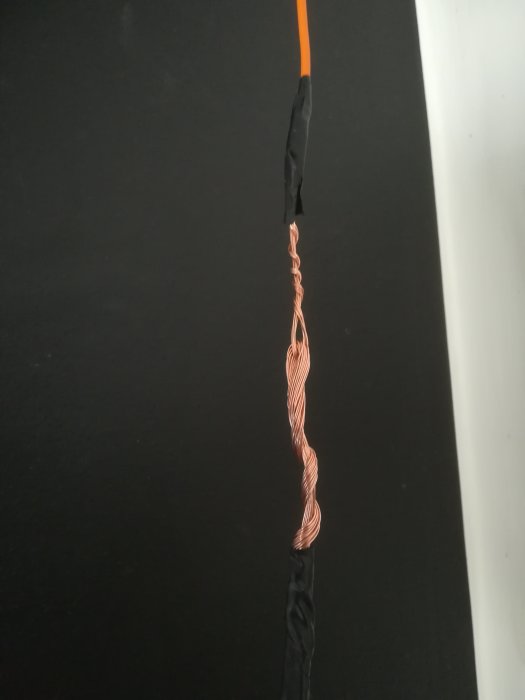 Sammanlänkade elektriska kablar med omspunna kopparkärnor och isolerad med svart tejp.