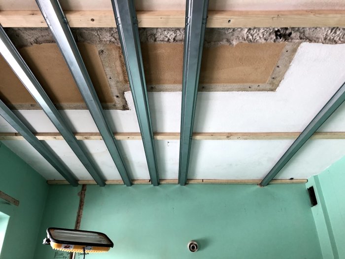 Konstruktion av sänkt tak med 28x70 träläkt och Norgips stålprofiler mot betongtak.