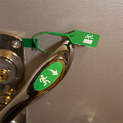 Utrymningshandtag med en kätting som håller en grön tagg märkt med en utrymningssymbol.