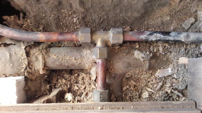 Gammalt 16 mm koppar varmvattenrör i T-kors som delas mot kök och oanvänt badrum.