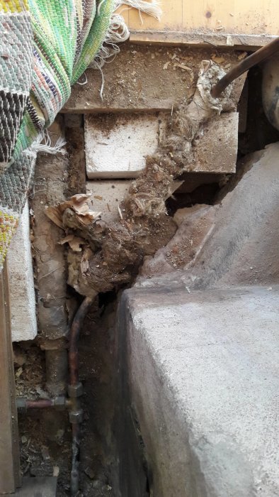 Ett 16 mm koppar varmvattenrör delas i ett T-kors, med isolering och äldre konstruktion synlig i ett hus.