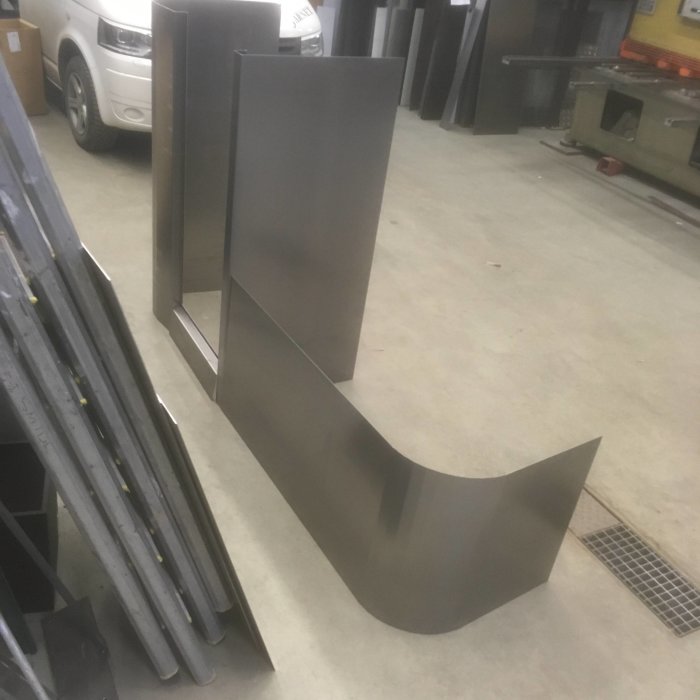 Bockade metallplåtsdetaljer i en verkstad, inklusive en tröskelbit med lutning och andra konstruktionsdelar.