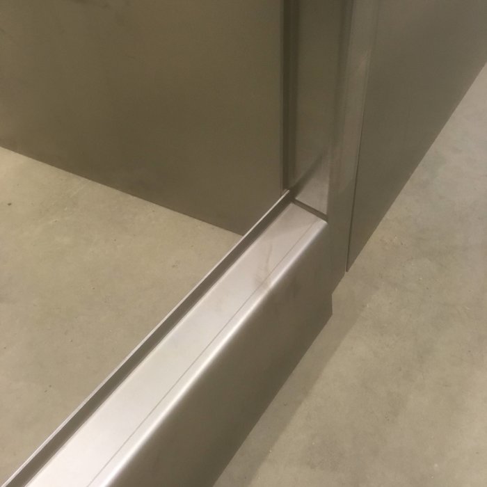 Metalldetalj med ca 20 graders lutning vid dörrkarm, tillverkad för vattenavrinning.