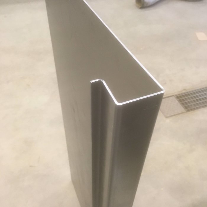 Böjd metallprofil som kan vara en tröskelbit med ca 20 graders lutning i ett byggprojekt.