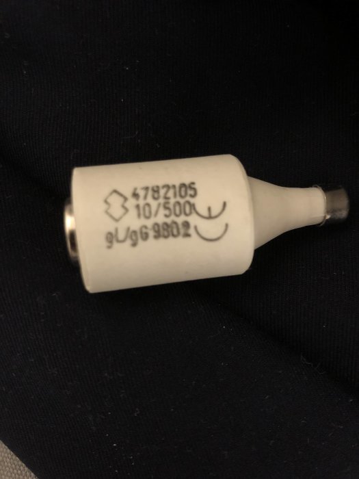 Säkring märkt "10/500U" hålls mot en mörk bakgrund, möjligtvis relaterad till diskussionen om elinstallation i garage.
