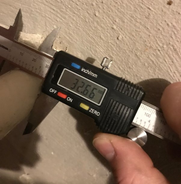 Digital skjutmått visar 32,66 mm mätning på ett rör med personens hand.