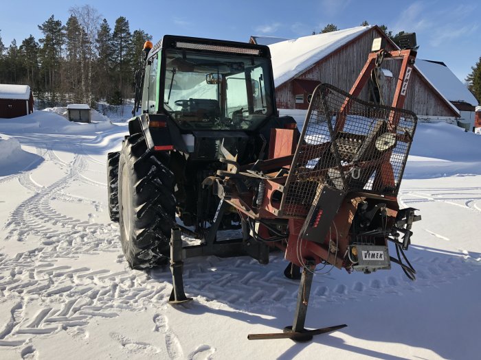 Valmet 6400 traktor med Vimek G30 processor i snöigt landskap framför röd lada.