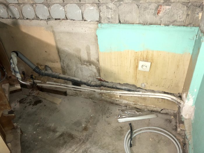 Ett 50 mm avloppsrör med en skarp 90-gradersböj genom en köksvägg under renovering.