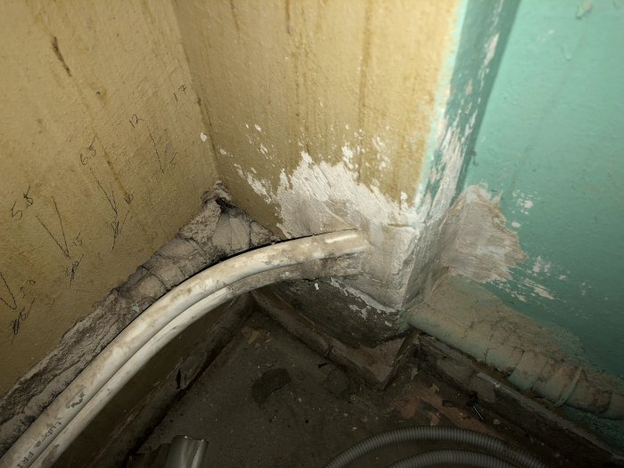 Avloppsrör med skarp 90-gradersböj går genom en vägg i en lägenhets renoveringsprojekt.
