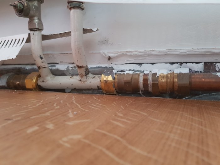 Värmeelement med kopparfogar och rör, vänstersida nyligen installerad, högra sida äldre.