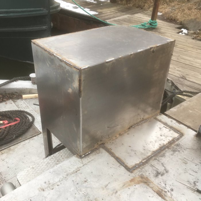 En svetsad metallkista på en byggplats med byggmaterial i bakgrunden.
