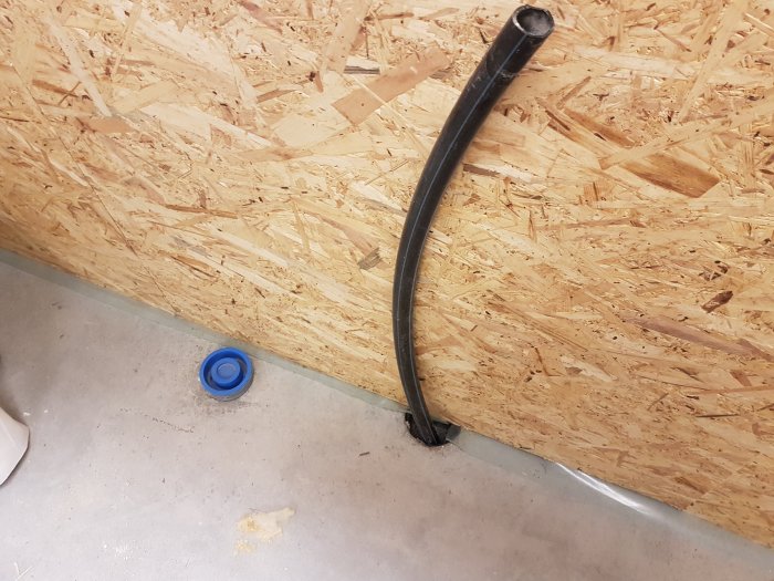 Gjuten platta i garage med förberett rör för el och avlopp samt blå lock på golvet.