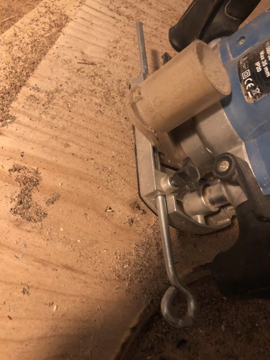 Handöverfräs med modifierad fönsterhake skapar runt hål i träplankan.