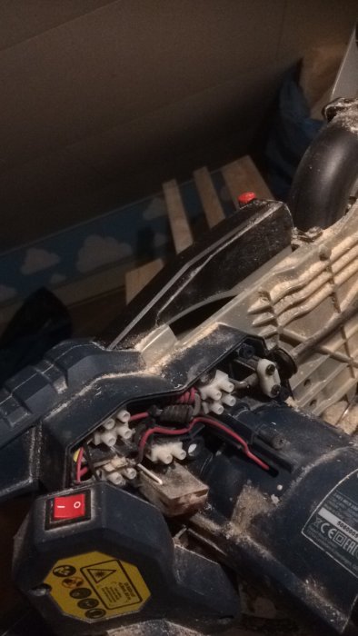 En öppnad elektrisk enhet med synlig kablage och motor, smutsig från användning.
