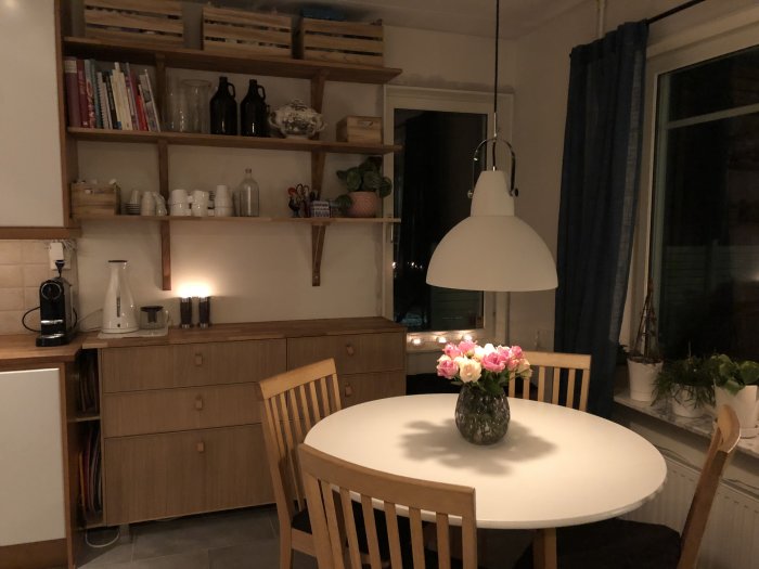 Renoverat kök med matplats, hyllor från Bauhaus, Ikea-lådor och fönsterutsikt mot skogen.