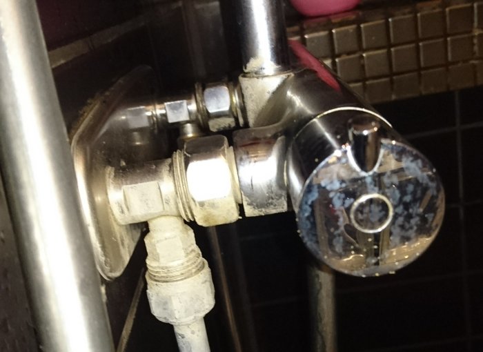 En använd duschblandare av okänt fabrikat med synlig termostat och vattenanslutningar.