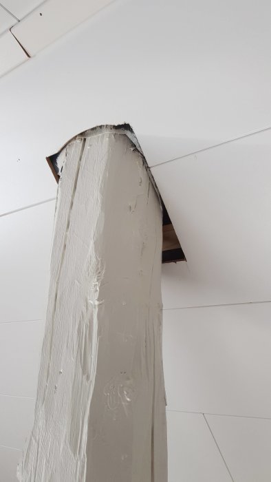 Rund, hvitmalt stolpe går gjennom hvitt tak med ujevnt hull, diskutert potensial for lister eller tetting.