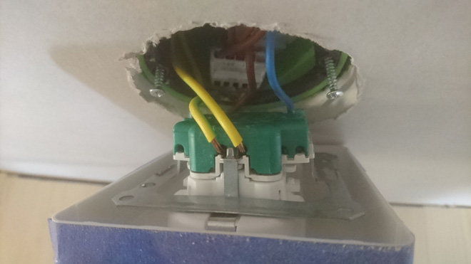 Öppet eluttag med exponerade elektriska kopplingar i en oavslutad vägginstallation.