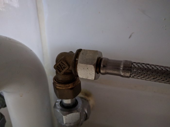 VVS-installation med gamla softPEX rörkoppling med mutteranslutning mot en vit bakgrund.