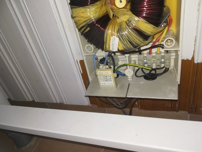 Transformator för golvvärme med oinkopplad jordtråd och elektriska anslutningar i ett badrum.