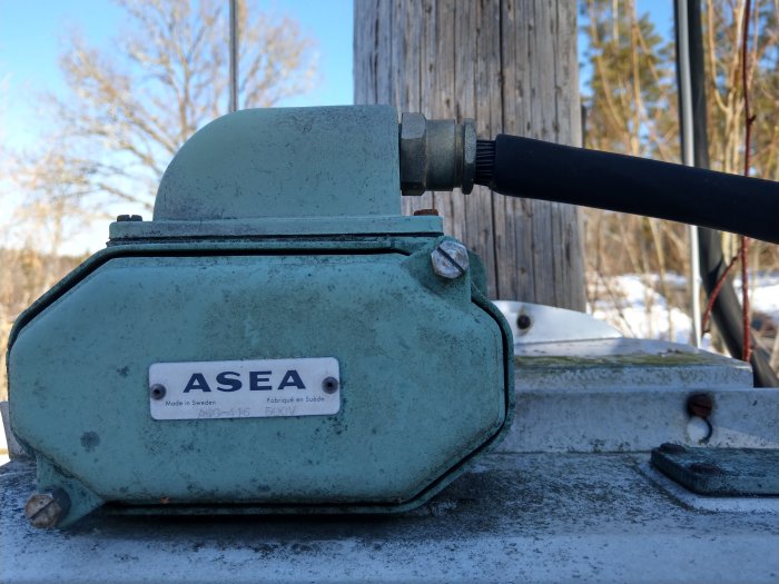 Gammalt ASEA elskåp på stolpe med skadad kabelisolering och synlig blottad mantel.