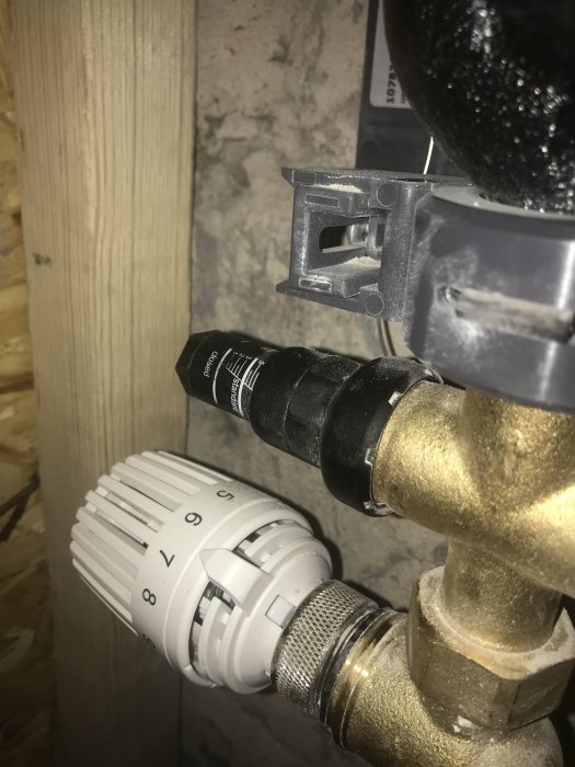 Termostatventil på radiator med inställningsskala och synliga röranslutningar.