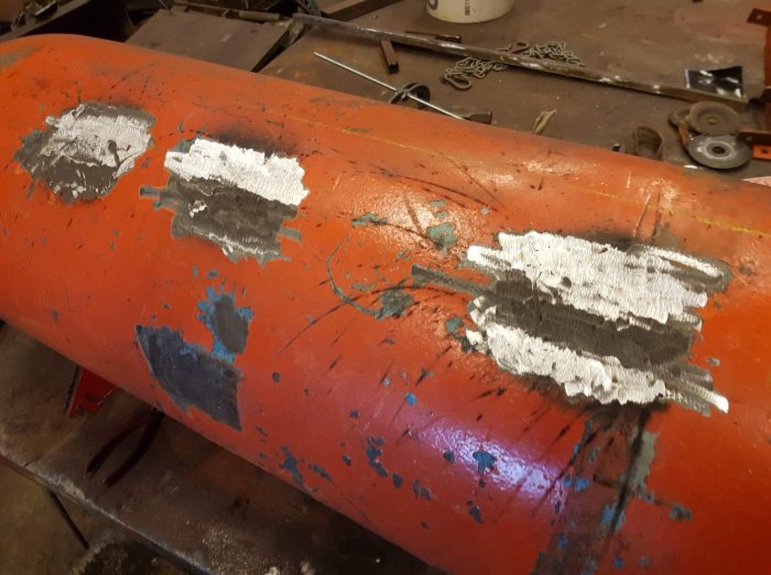 Svetsfogar på en röd metallyta som visar nyligen avslutat svetsarbete, med vissa svetsrester som ska slipas bort.