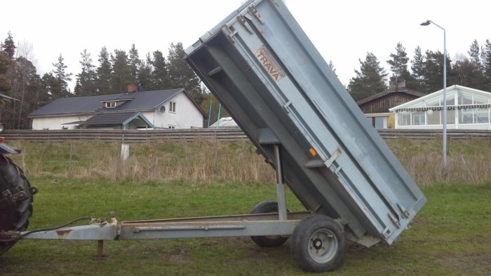 Tippkärra av märket Trava Weckman i upptippat läge på en gräsmatta.