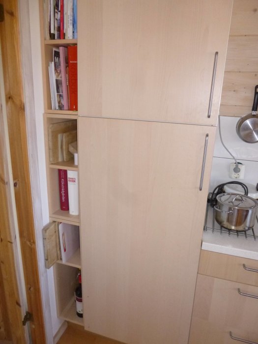 Anpassat Ikea-skåp på 160 mm fyller utrymme bredvid diskmaskin med böcker och köksredskap.