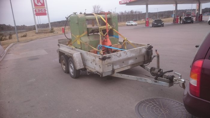 En Jonsered planhyvel fastsäkrad på ett nyligen inköpt släp parkerat vid en bensinstation.