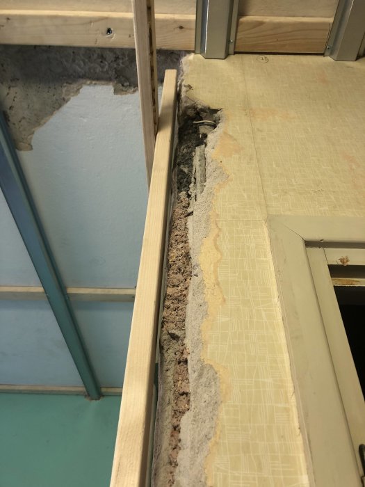 Ojämnt hörn av slaggbetong och puts bredvid träregel, med synligt reglararbete inför gips- och OSB-montering.