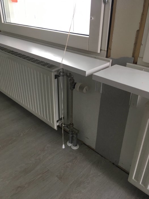 Renoverat vardagsrum med radiator och ny fönsterbräda som kräver justeringar vid installation.